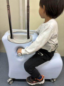 キッズトラベルキャリーに子どもが乗っている
